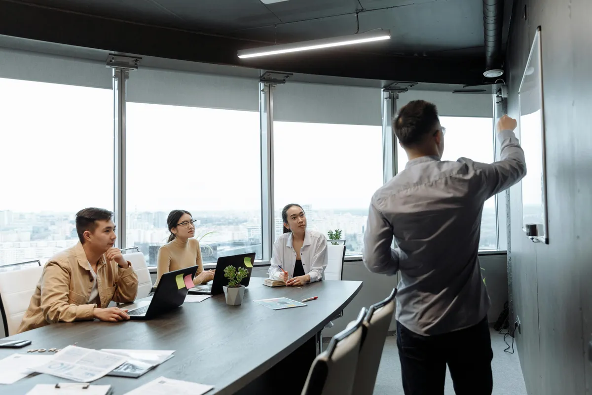 Formateur présentant un tableau devant des apprenants en salle de formation